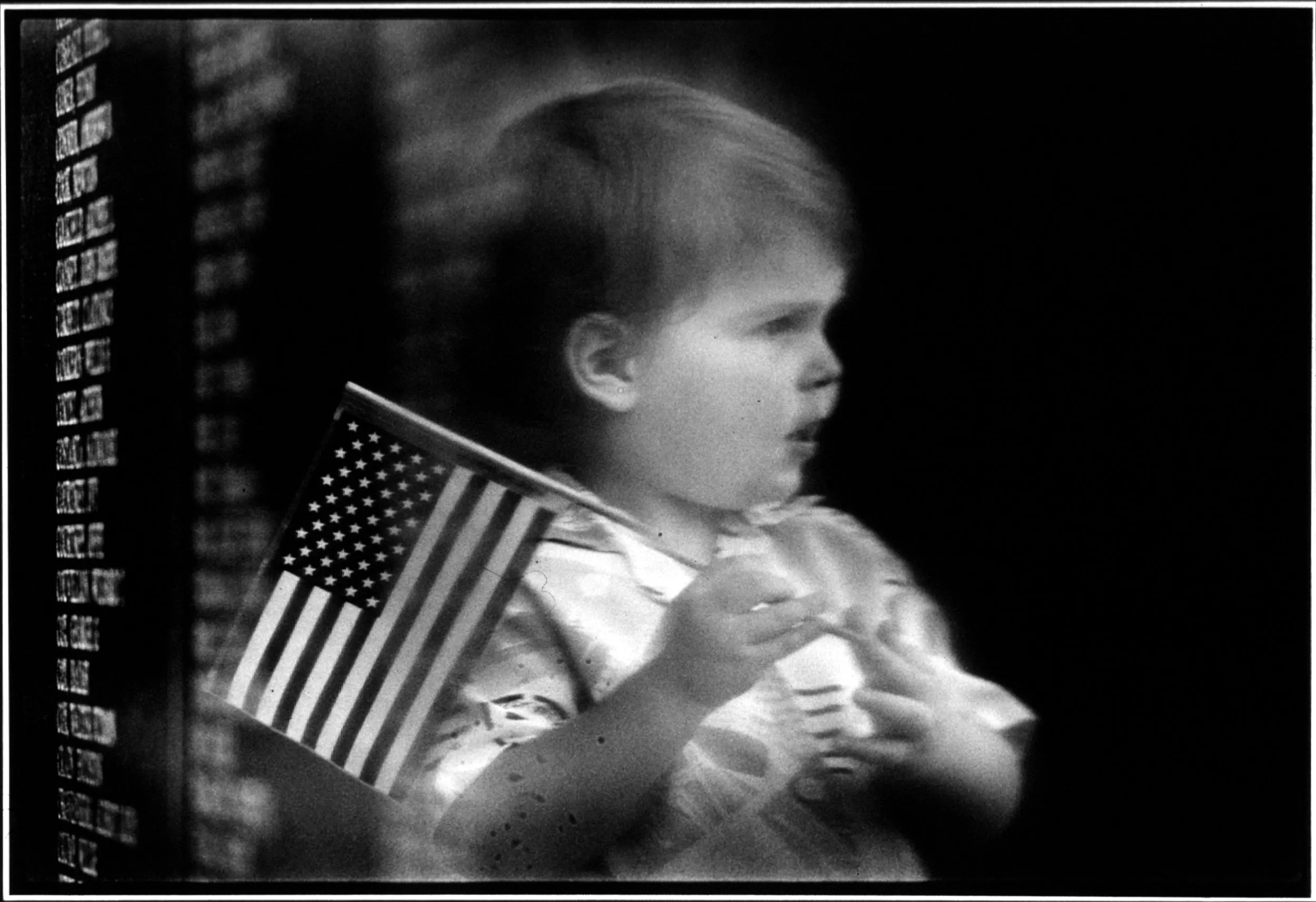 A Future Honors The Past — Brad Bennet, nearly two years old, is reflected in the smooth black marble of the Louisiana War Memorial. Brad's image is framed between the memorial's black marble and the etched names of Louisiana soldiers who lost their lives in all wars since the civil war.  (Photo by Stephan Savoia)  Published by The Baton Rouge Louisiana State-Times & Morning Advocate Circa Mid 1980s