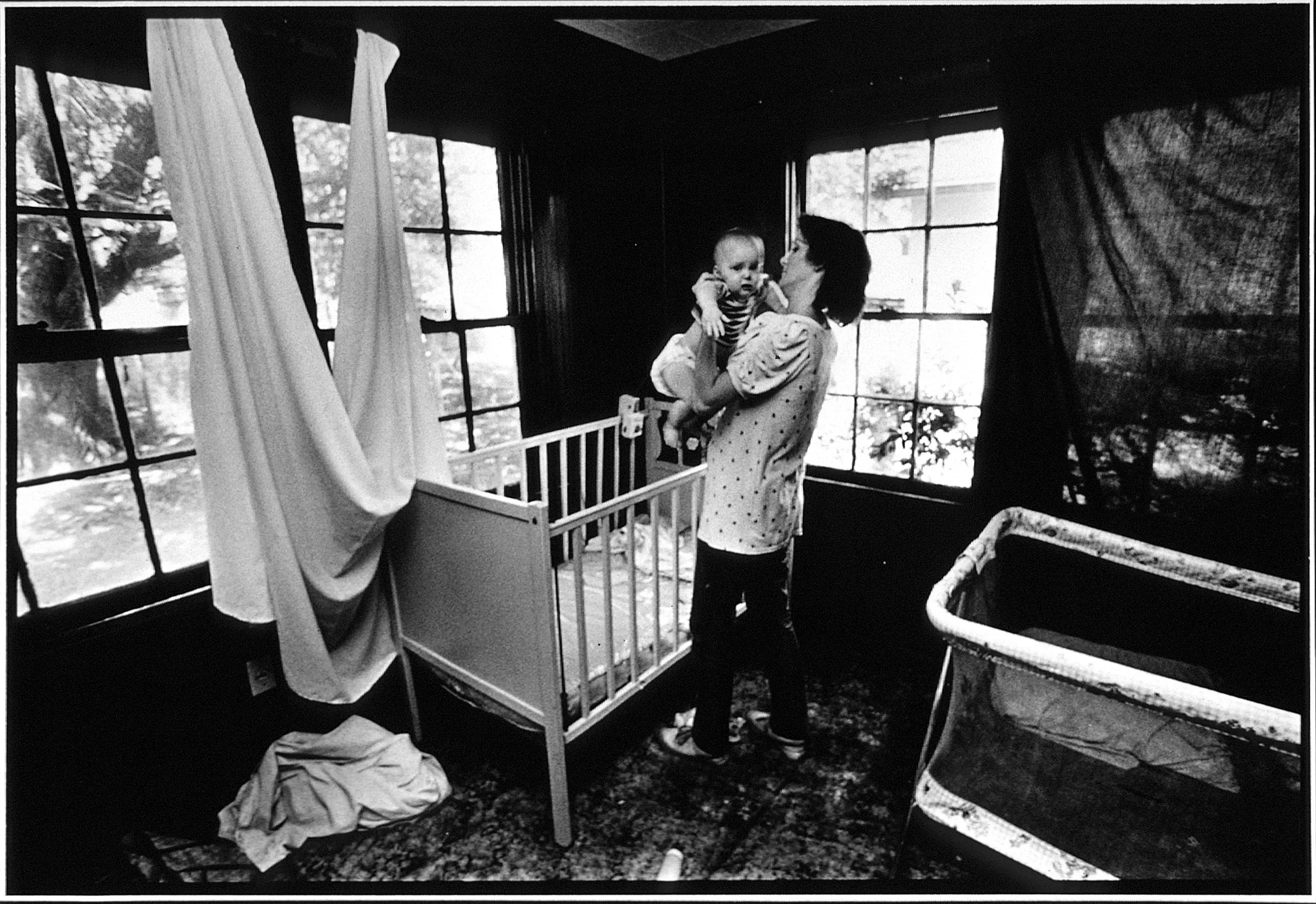 Poverty's Nursery — Deborah LaBoyteaux, 23, a divorced unemployed young mother of three children, while pregnant with her fourth child, lifts her 10-month-old son John from his crib in the child's bedroom / nursery after a nap in Baton Rouge, Louisiana. LaBoyteaux says of her life, “I guess I liked the idea of playing house. I was not thinking of the responsibilities of having babies.”  (Photo by Stephan Savoia)  Published by The Baton Rouge Louisiana Sunday Advocate Magazine on October 19, 1986