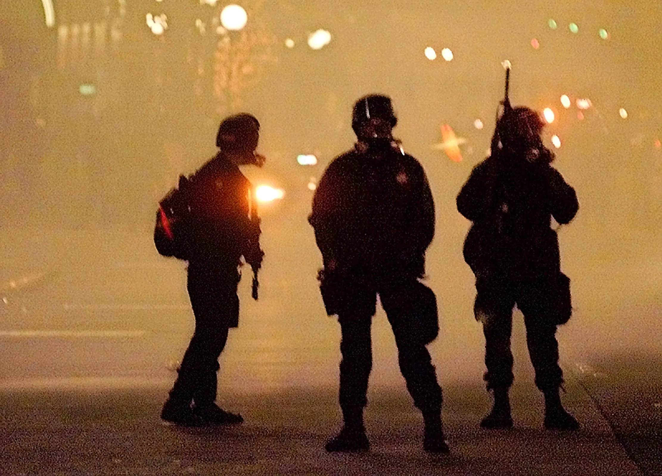 Downtown Seattle — Police officers from the sheriff's department, dressed in riot gear and enveloped in a cloud of tear gas, move north on 3rd Avenue in Seattle, Washington pushing World Trade Organization protestors away from the downtown area Tuesday evening, November 30, 1999. WTO protests, both peaceful and violent, continue to clog city streets while crippling the WTO conference.  (AP Photo/Stephan Savoia)  © The Associated Press