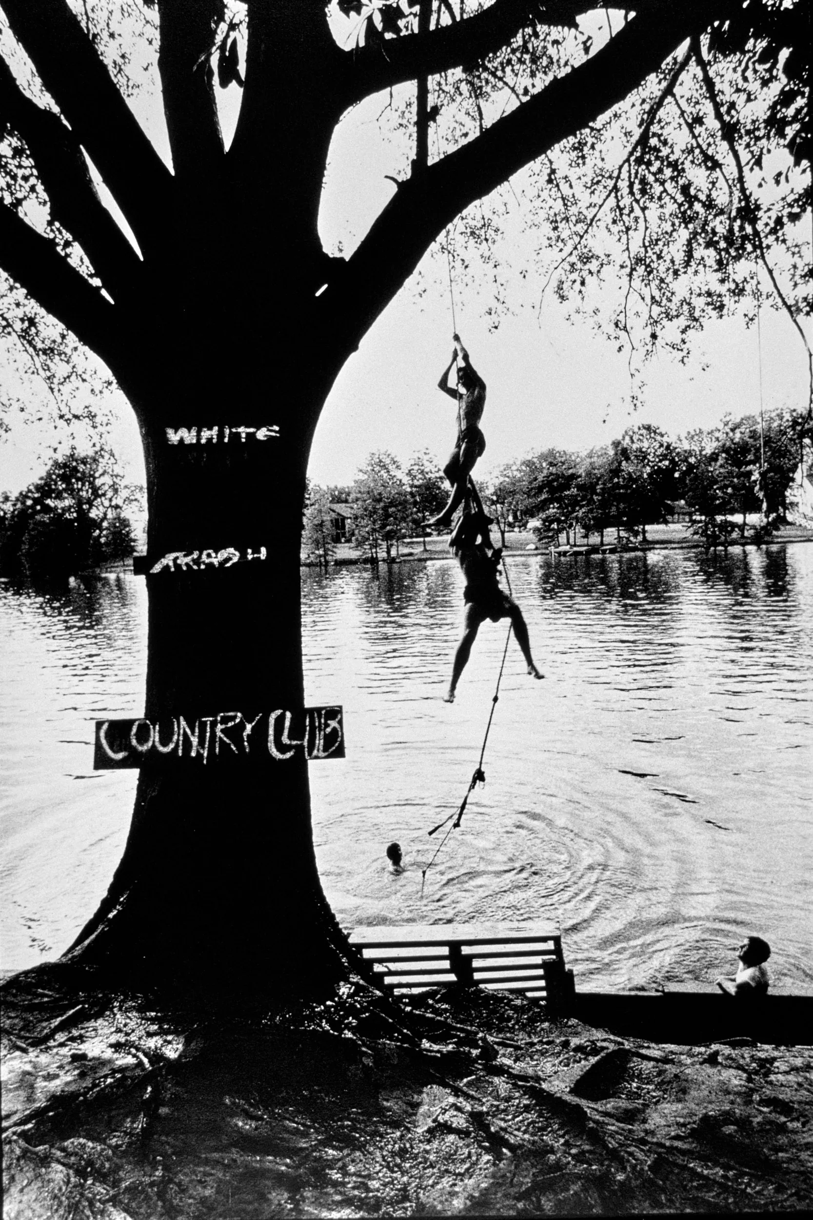 White Trash Country Club — Teenage boys swing from a tree-rope before dropping into Bayou Desiard in Ouachita Parish near Monroe, Louisiana.  (Photo by Stephan Savoia)  Published by The Monroe News-Star-World Circa Early 1980s