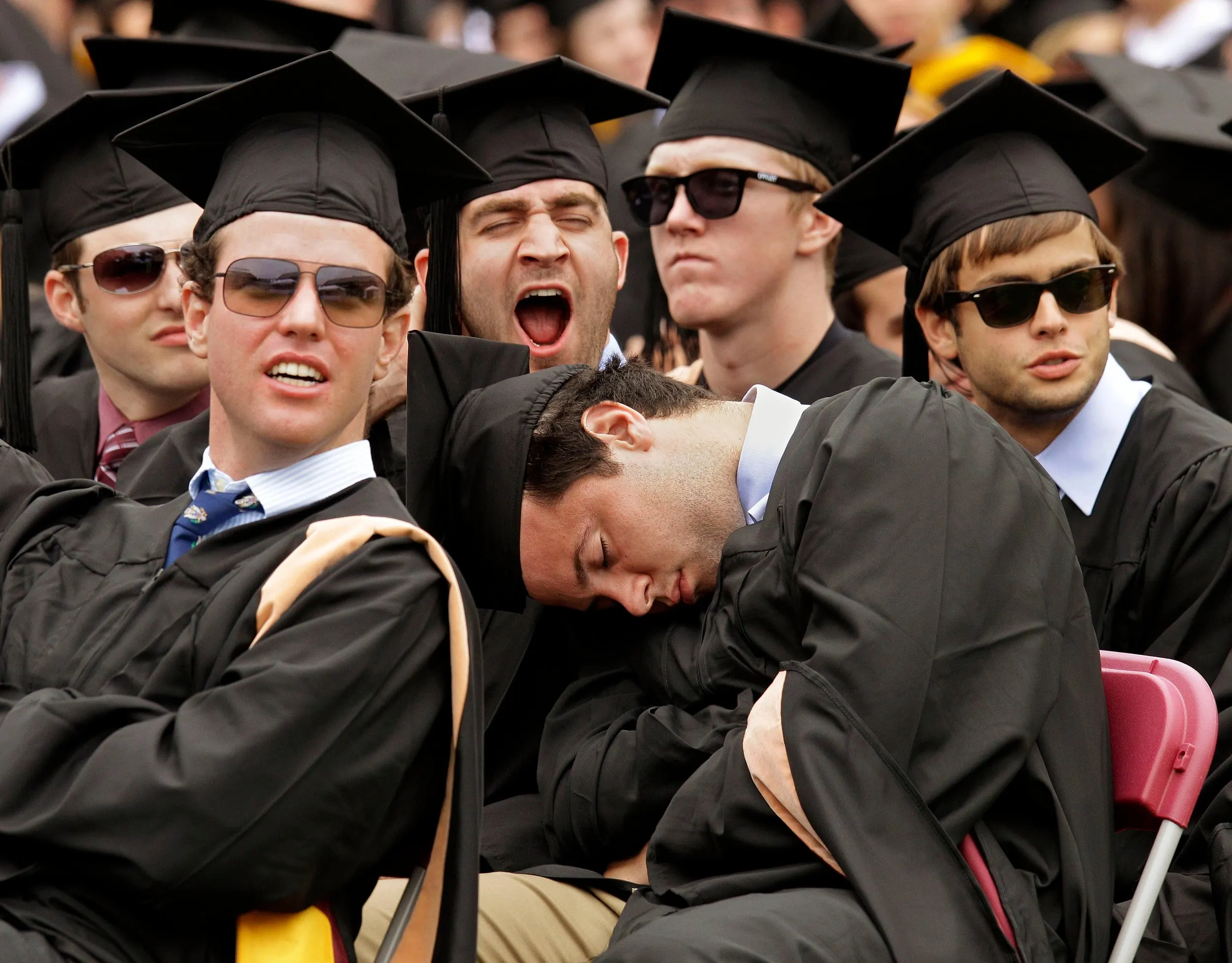 Hangover — John Fiorenzo, center, catches a brief nap during the address to the graduates at his Boston College Commencement ceremony while a classmate yawns behind him at Alumni Stadium on the university's campus in Boston, Massachsetts on Monday, May 21, 2012. Fellow graduates Patrick Dingham, left, and Brandan Kirby, right, watch the stadium's scoreboard jumbotron. All of the men received their Bachelors of Science degrees from the university's Carrol School of Management.  (AP Photo/Stephan Savoia)  © The Associated Press