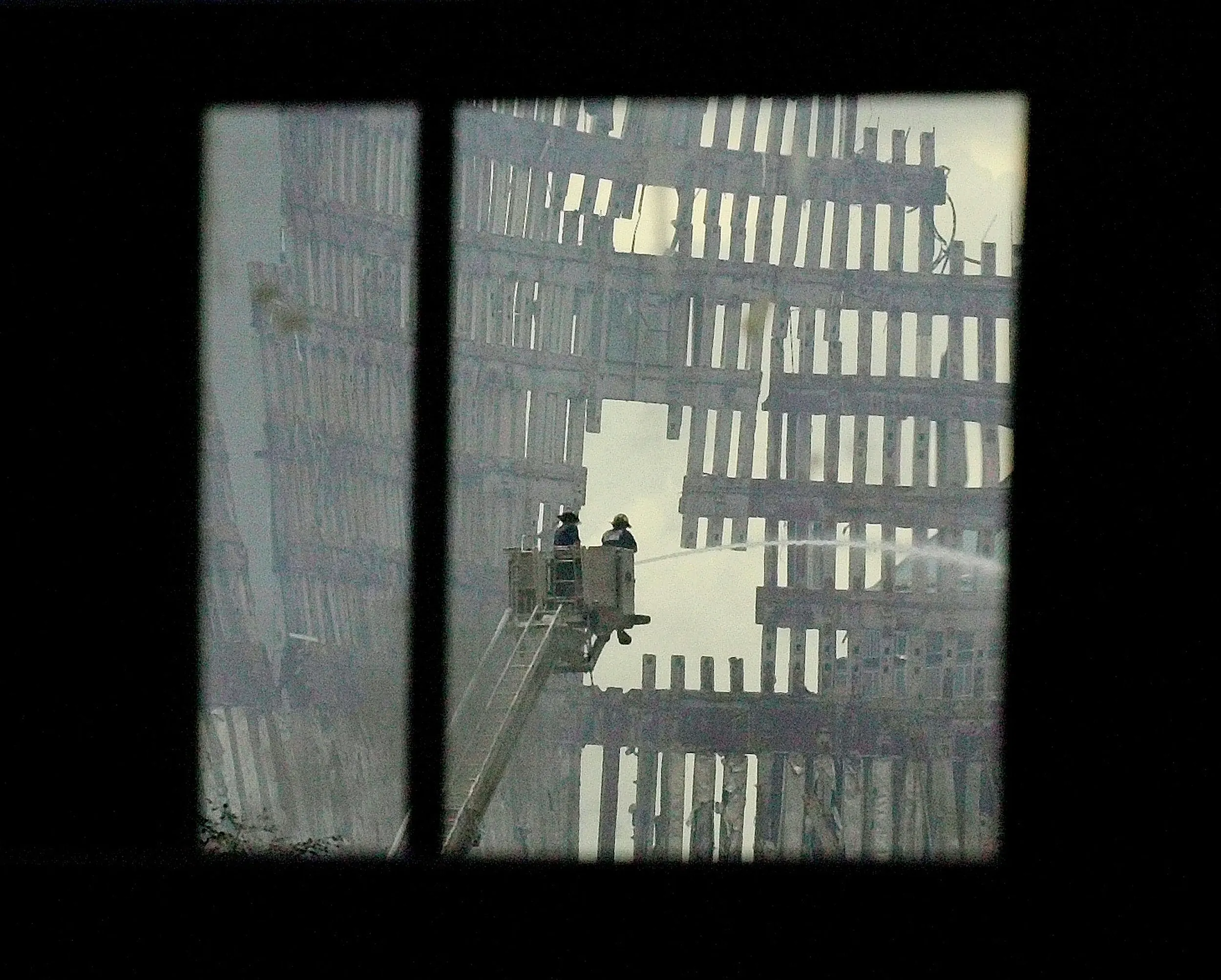 After The Fall — Firemen are seen spraying water on the smoldering ruins of the World Trade Center through the window of a New York City Transit Authority bus parked on the corner of Maiden Street and Broadway in New York City's lower Manhattan Tuesday afternoon September 25, 2001. City buses were placed across several cross streets on Broadway to block the view of the fallen towers while members of the New York City police department and National Guard told spectators and members of the press to keep moving saying pictures are not allowed.  (AP Photo/Stephan Savoia)  © The Associated Press