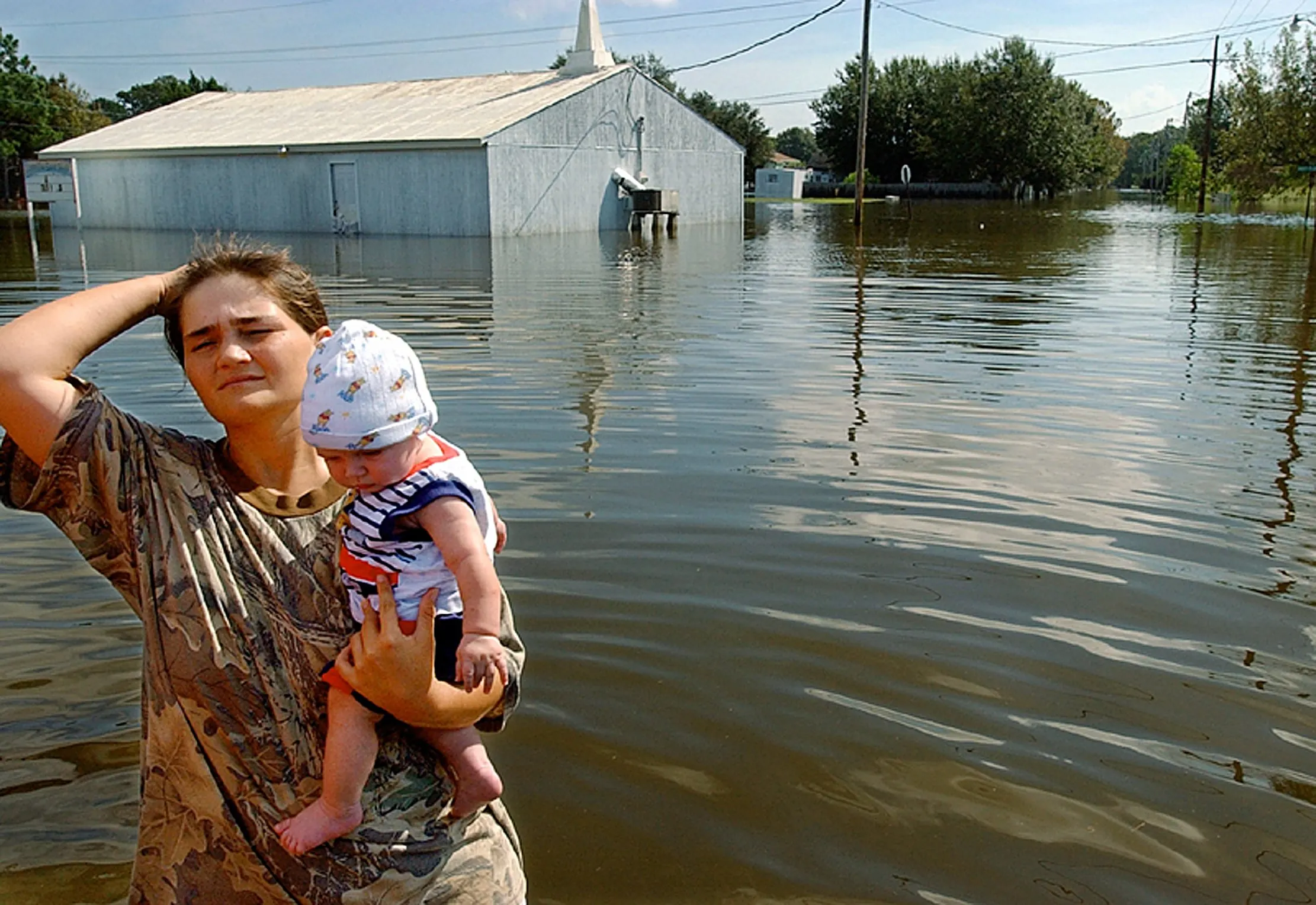 “High Black Water, The Devil's Daughter” — Holding her four-month-old son Kevin Hebert, Tracey Ledet brushes back her hair as she waits in the hot sun for a boat to take her and her young son to their flooded home on Roland Henery Street in Montegut, Louisiana, Friday morning, October 4, 2002. Flood waters brought by Hurricane Lili caused extensive damage to the community of 4,000.  (AP Photo/Stephan Savoia)  © The Associated Press